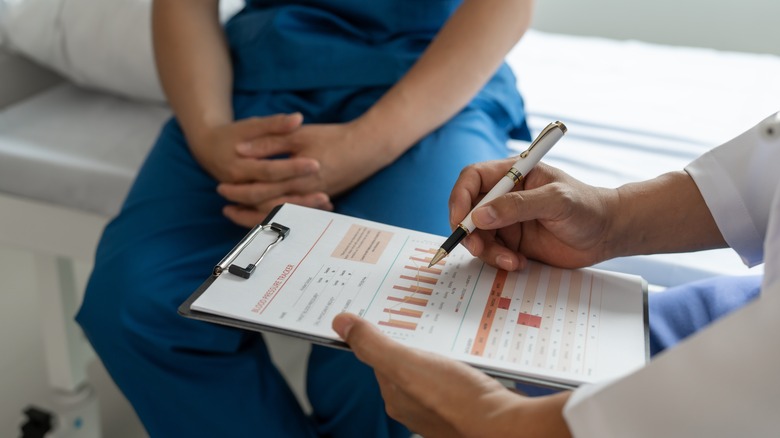 doctor holding clipboard near patient