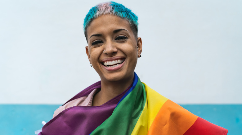 woman smiling and holding rainbow flag
