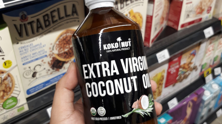 hand holding bottle of coconut oil in grocery store