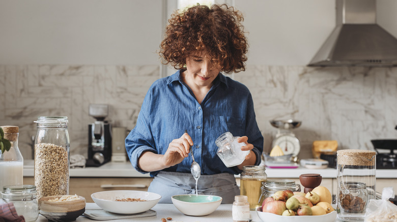 smiling woman in kitchen using coconut oil for food