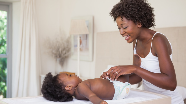 Smiling mother changing baby's diaper