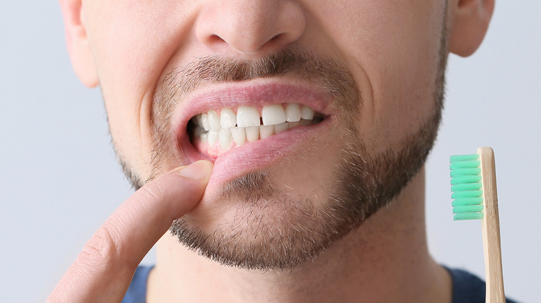 white man with painful tooth holding toothbrush