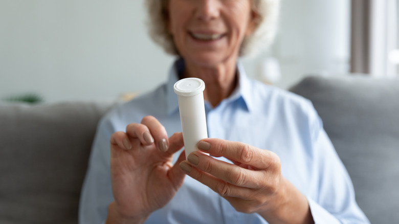 Smiling older woman reading pill bottle