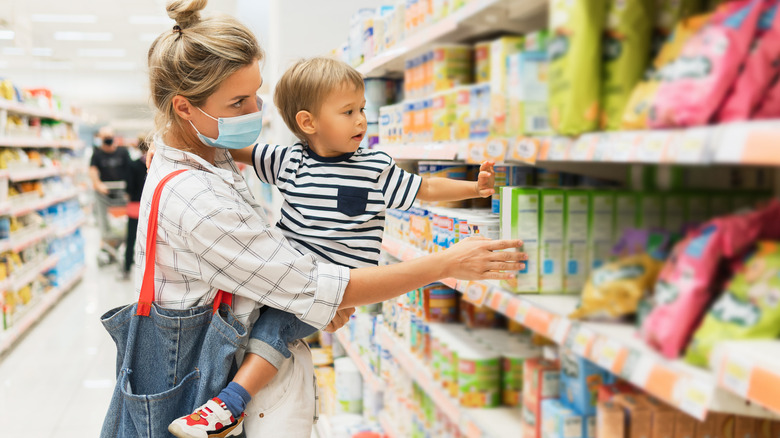 Masked mother and unmasked young son grocery shopping