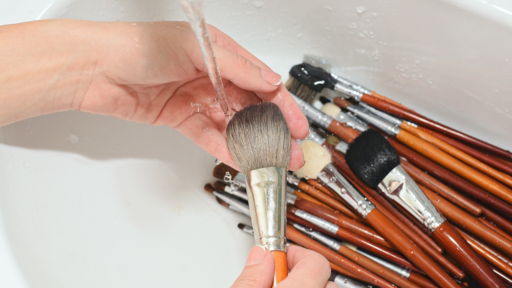 a hand cleaning make-up brushes in the sink