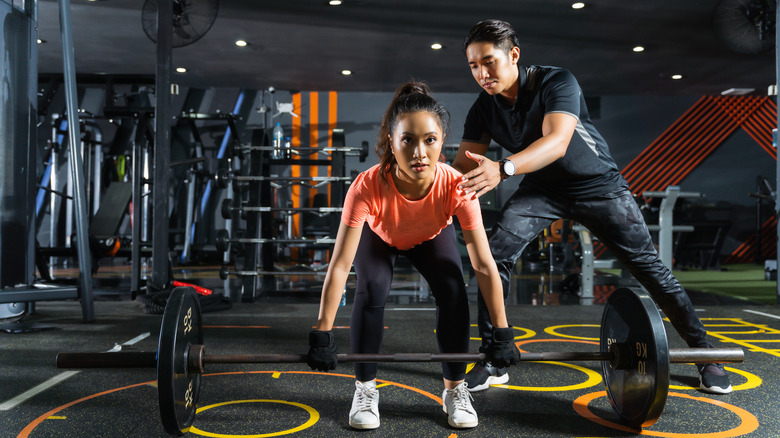 Personal trainer showing his client how to deadlift