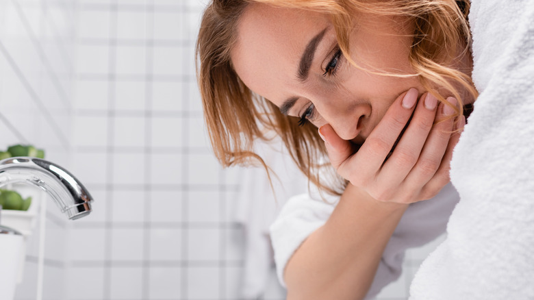 Woman covering her mouth vomiting