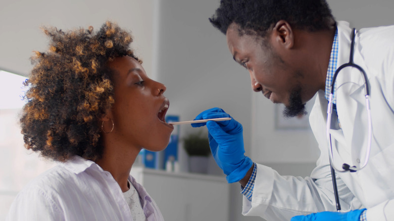 black doctor examining patient's throat