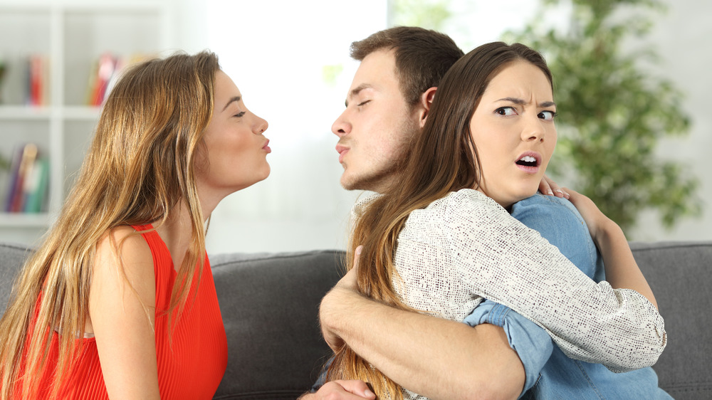 Man ignoring girlfriend, trying to kiss another woman