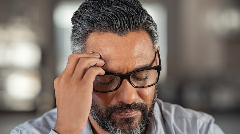 man with closed eyes and hand on forehead