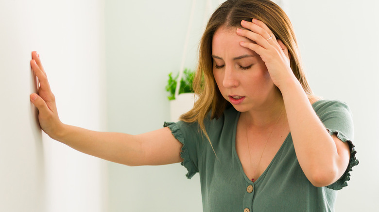 Young woman steadying self against wall