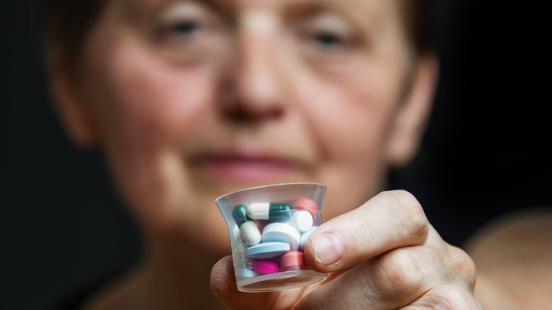 Woman holding multiple pills in small container