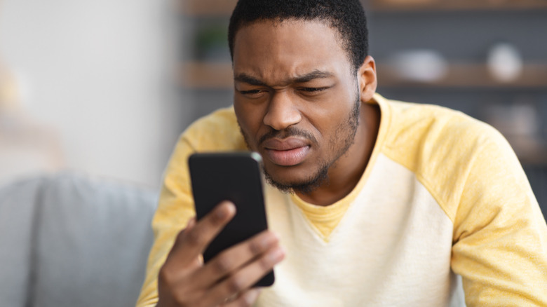 Man squinting at cell phone