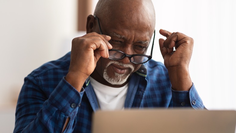 Man looking over his glasses at laptop
