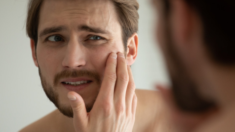 man looking at his skin