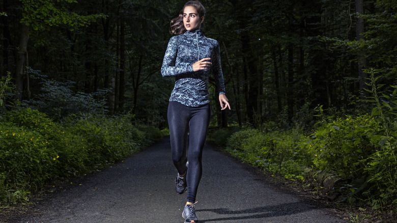 Woman running in a dark forest