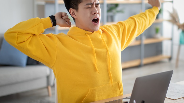 Tired man at computer yawning