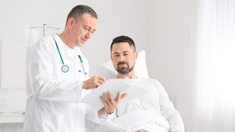 man sitting in a hospital bed talking to doctor 