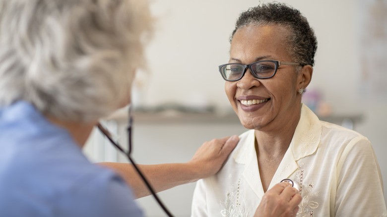 Doctor using stethoscope on smiling patient