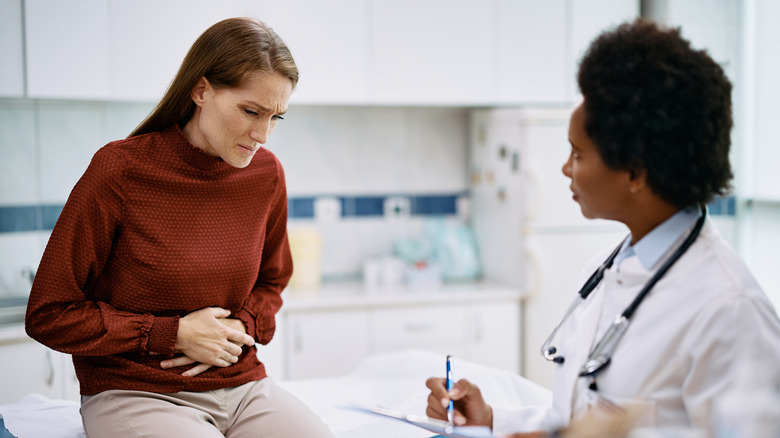 Woman with stomach ache talking to doctor