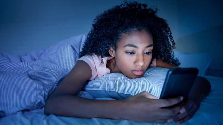 child holding phone in bed before sleep