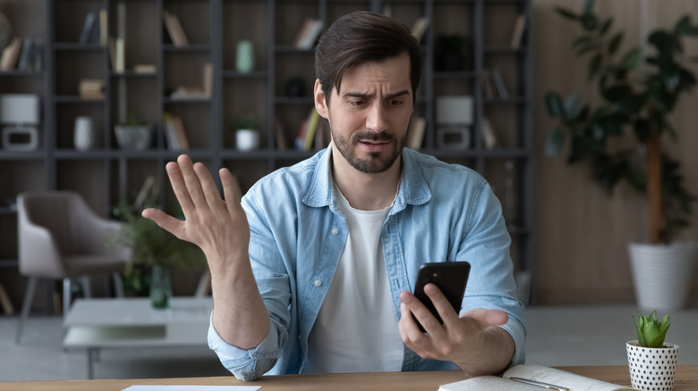 confused man looking at smartphone