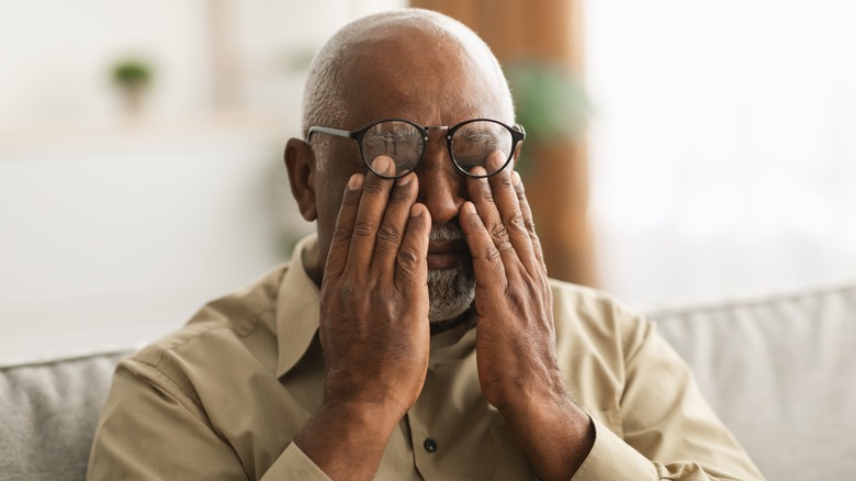 older man rubbing tired eyes 