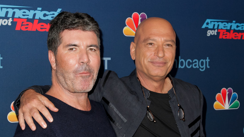 Simon Cowell stands next to Howie Mandel