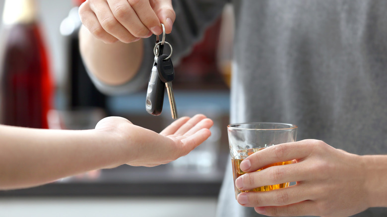 Man drinking hands car keys to designated driver.