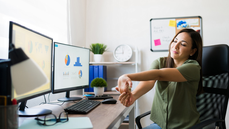 person stretching their wrist at desk