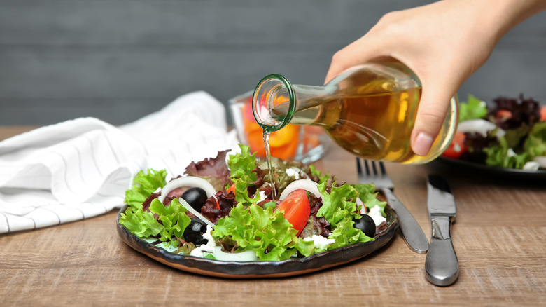 pouring apple cider vinaigrette onto salad