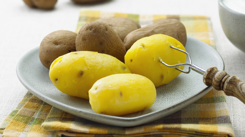 Raw and peeled boiled potatoes on a plate