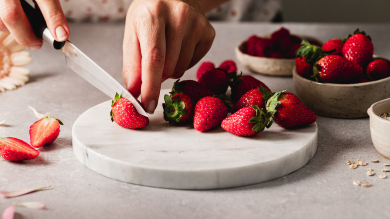 hands slicing strawberries