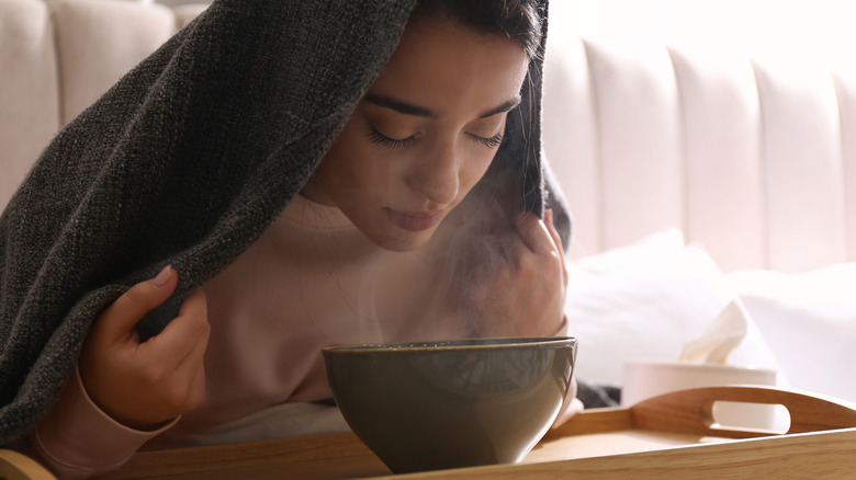 Woman inhaling steam from a bowl of hot water