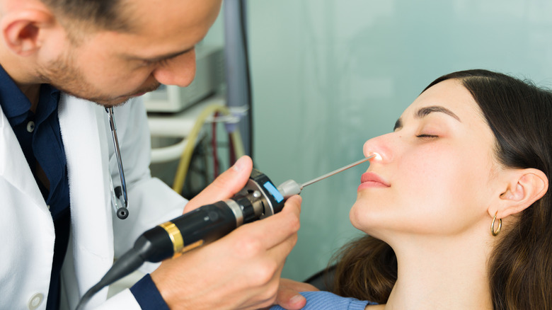 doctor examining nose with lighted scope