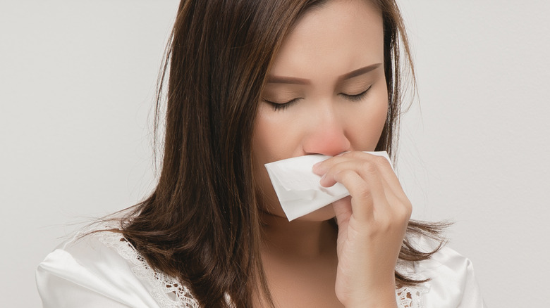 sick female blowing irritated nose