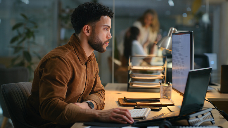 man at desk looking at laptop in office