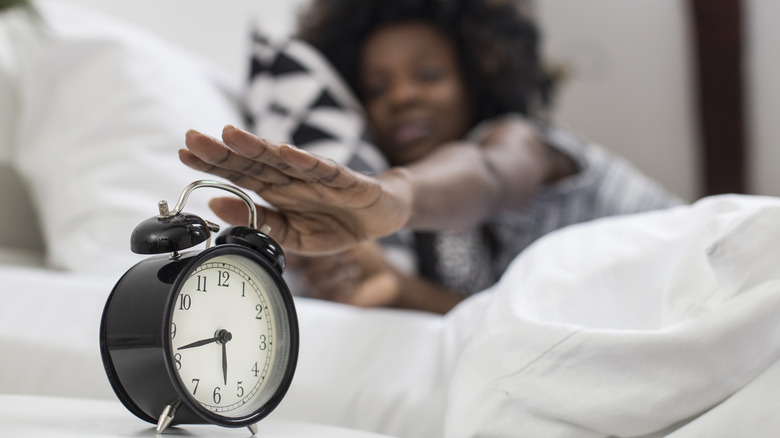 woman turning off her alarm clock