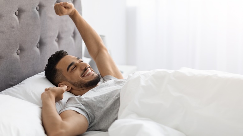 Man smiling waking up in bed well rested