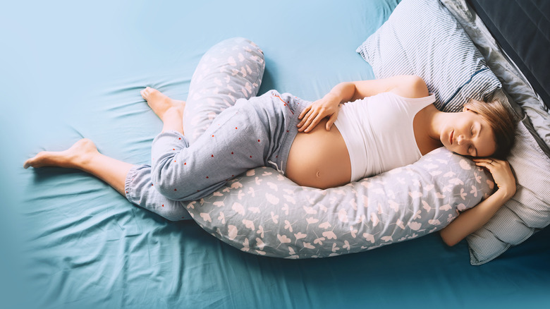 pregnant woman cuddling pregnancy pillow 