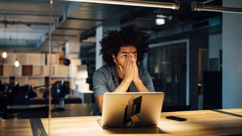 stressed out man holding his face at work