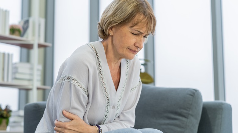 Woman in pain seated on couch