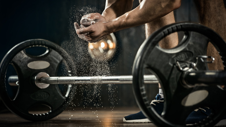 man chalking hands over barbell