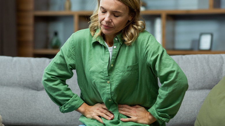 unhappy woman on couch with stomach ache