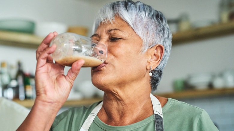 woman with salt and pepper hair drinking smoothie