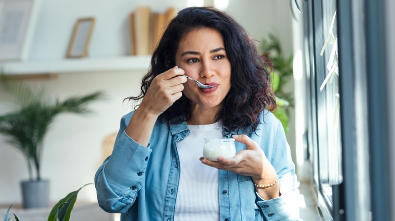 Smiling woman eating spoonful of yogurt