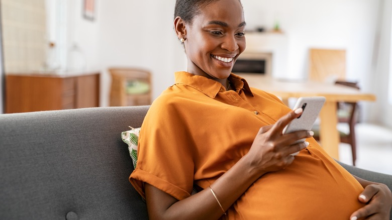 A pregnant woman looks at her phone