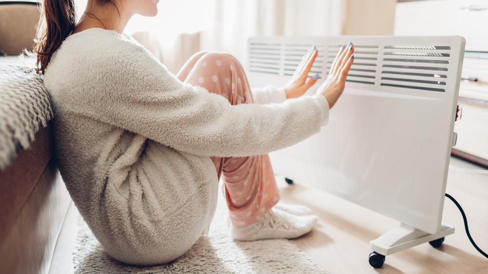 A woman warming her feet by a heater