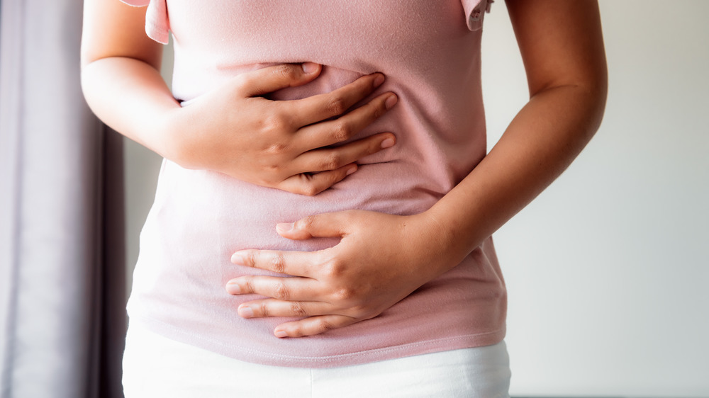 A bloated woman grabbing her stomach