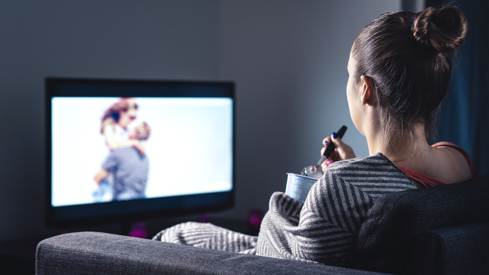 woman watching tv while eating ice cream